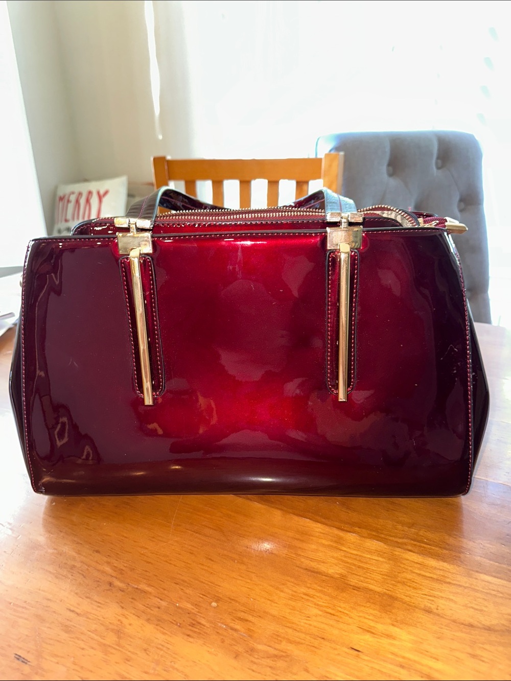 burgundy patent satchel handbag. It features a high-gloss finish